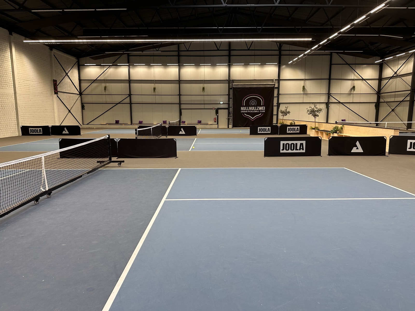 Mehrere Indoor-Pickleball-Courts mit der Aufschrift NULLNULLZWEI Urban Pickleball Club in Heidelberg