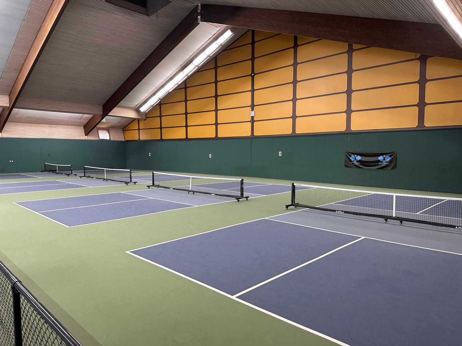 Indoor-Pickleball-Courts mit Holz-Dach und Top-Pickleball-League-Banner bei Top Pickleball Stuttgart in Ostfildern